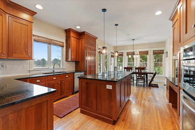 kitchen with a center island, stainless steel dishwasher, decorative light fixtures, decorative backsplash, and light wood-type flooring