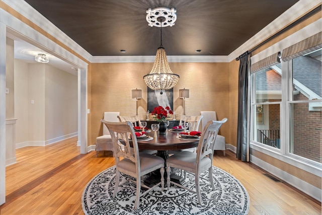 dining area with an inviting chandelier, ornamental molding, and light wood-type flooring