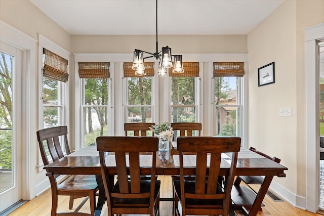 dining area with light wood-type flooring and a notable chandelier