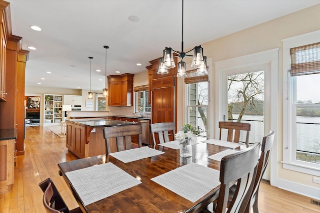 dining room with light hardwood / wood-style floors, sink, and a chandelier