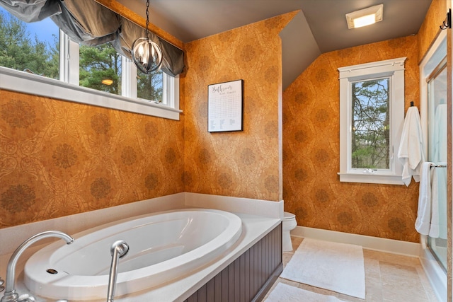 bathroom featuring toilet, a bath, and a chandelier