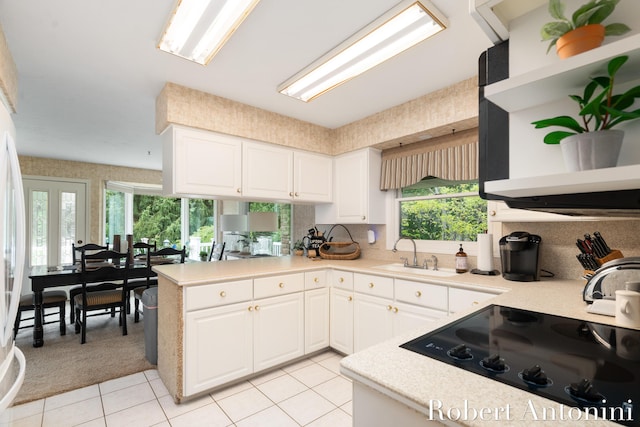 kitchen with kitchen peninsula, sink, white cabinetry, black cooktop, and light tile patterned floors