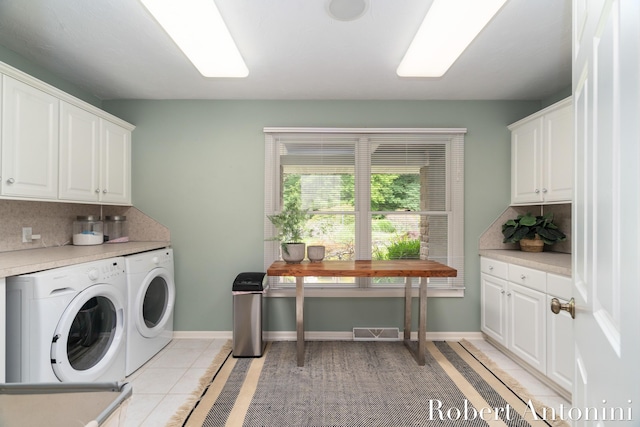 washroom featuring light tile patterned flooring, washing machine and clothes dryer, and cabinets