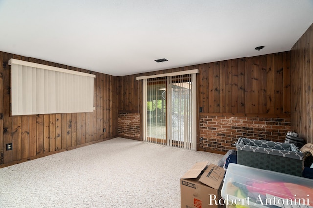 bedroom with carpet, access to exterior, brick wall, and wood walls