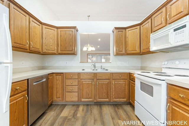 kitchen featuring sink, dark hardwood / wood-style floors, pendant lighting, a chandelier, and white appliances