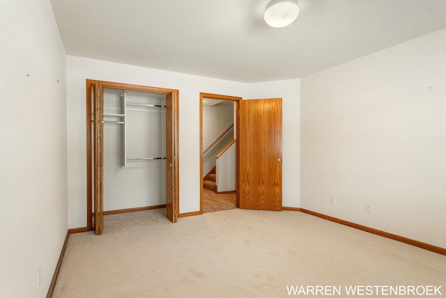 unfurnished bedroom with light colored carpet and a closet