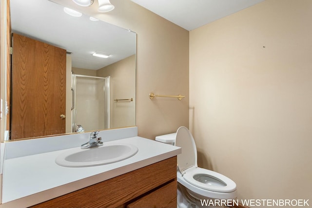 bathroom with a shower with door, vanity, and toilet