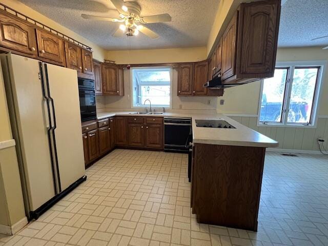 kitchen featuring ceiling fan, sink, kitchen peninsula, a textured ceiling, and black appliances