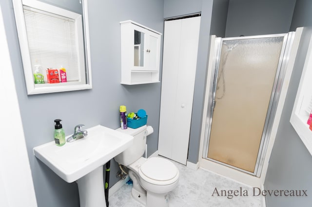 bathroom featuring toilet, a shower with shower door, and sink