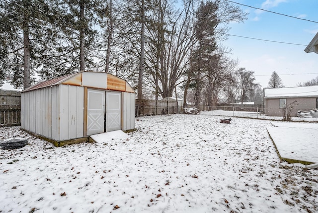 snowy yard featuring a storage unit