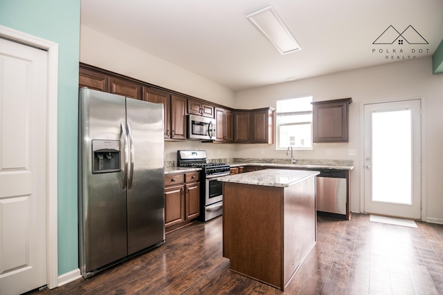 kitchen with light stone countertops, dark hardwood / wood-style flooring, a kitchen island, and stainless steel appliances