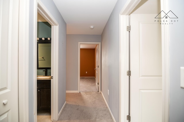 hallway featuring light carpet and sink