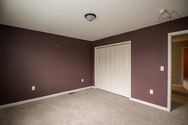 unfurnished bedroom featuring light carpet and a closet