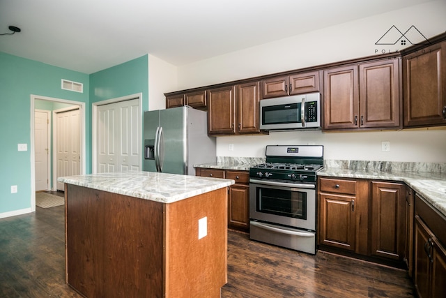 kitchen featuring light stone countertops, stainless steel appliances, a kitchen island, and dark hardwood / wood-style floors