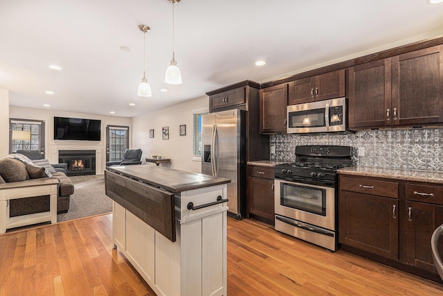 kitchen with dark brown cabinetry, decorative backsplash, and stainless steel appliances