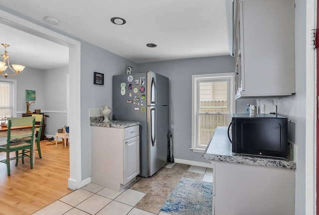 kitchen featuring white cabinetry, plenty of natural light, stainless steel fridge, and an inviting chandelier