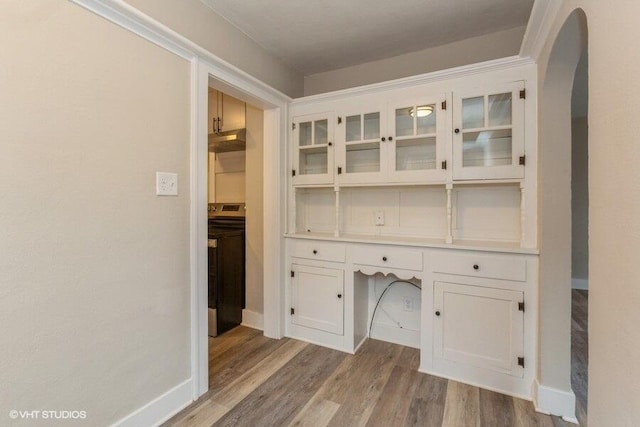 unfurnished office featuring built in desk, washer / clothes dryer, and light hardwood / wood-style flooring