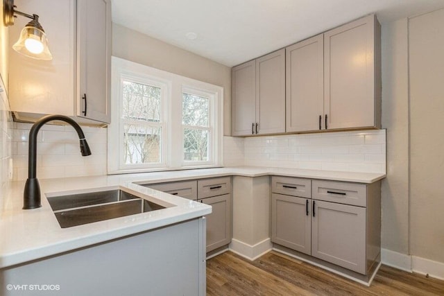 kitchen with tasteful backsplash, gray cabinetry, sink, and dark hardwood / wood-style floors