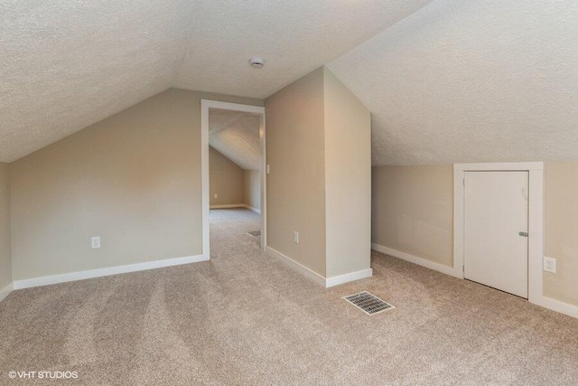 additional living space with light carpet, a textured ceiling, and vaulted ceiling