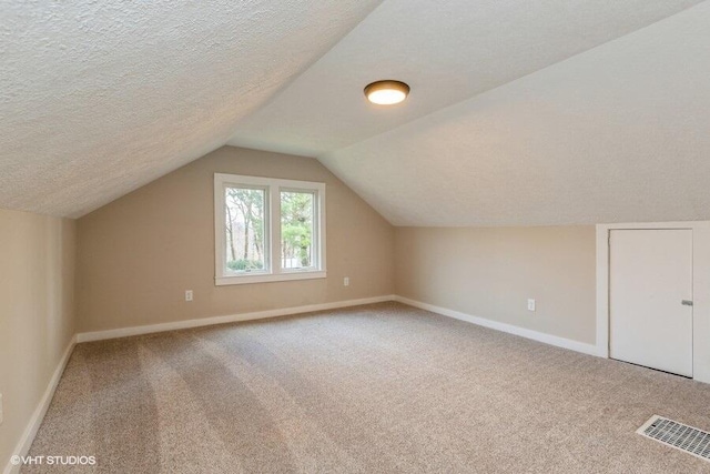 additional living space featuring carpet flooring, a textured ceiling, and lofted ceiling