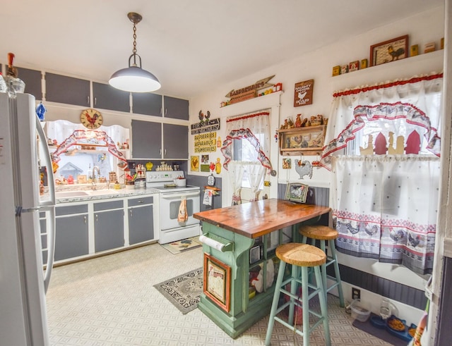 kitchen with decorative light fixtures, a kitchen breakfast bar, white appliances, and sink