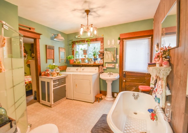 bathroom with a washtub, an inviting chandelier, double sink, and washing machine and clothes dryer