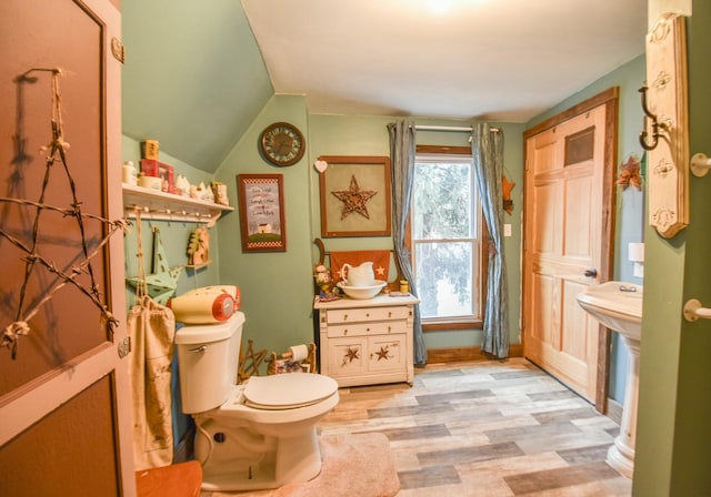 bathroom with hardwood / wood-style flooring, toilet, and vaulted ceiling