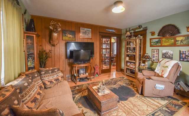 living room with wood walls, wood-type flooring, and french doors