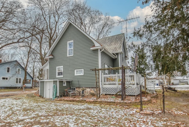 snow covered house featuring a wooden deck