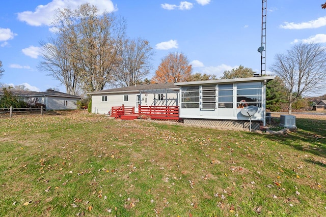 back of property featuring central air condition unit, a wooden deck, a sunroom, and a yard