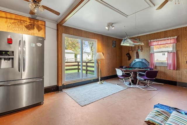 dining area featuring ceiling fan, crown molding, and wood walls