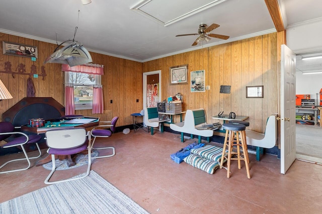 dining area featuring ceiling fan, crown molding, and wood walls