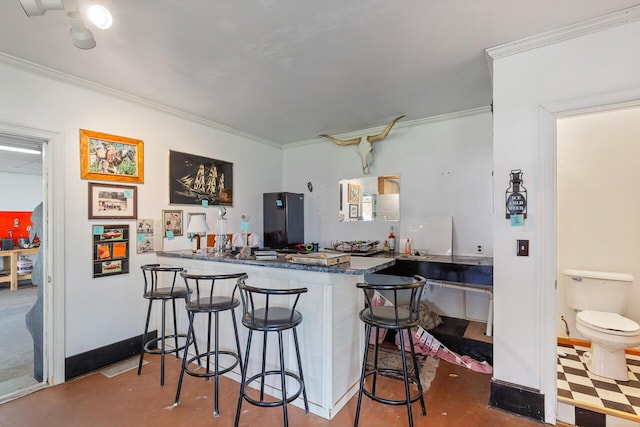 kitchen with a kitchen breakfast bar, kitchen peninsula, crown molding, and concrete floors