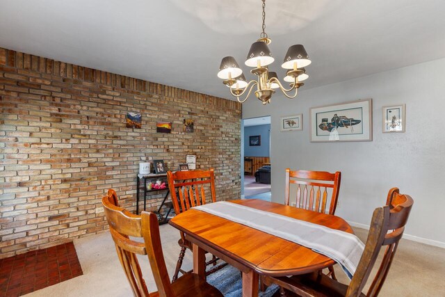 carpeted dining room featuring brick wall and a notable chandelier