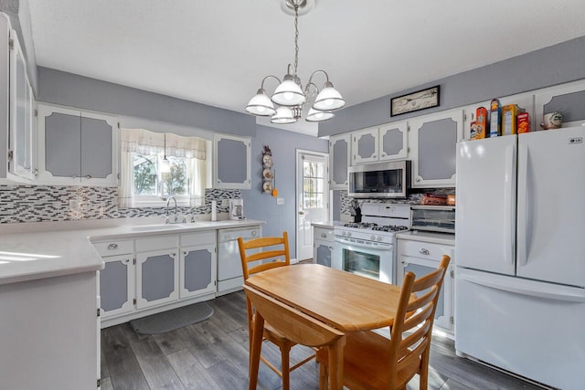 kitchen with plenty of natural light, sink, hanging light fixtures, and white appliances