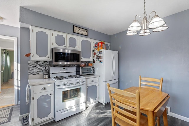 kitchen with decorative backsplash, white appliances, a chandelier, dark hardwood / wood-style floors, and white cabinetry