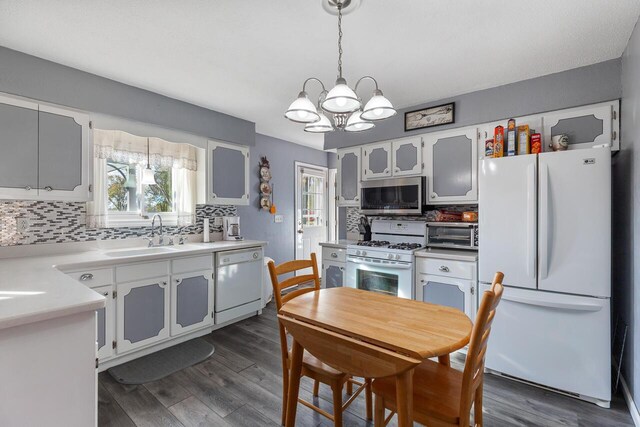 kitchen featuring pendant lighting, white appliances, white cabinets, sink, and tasteful backsplash