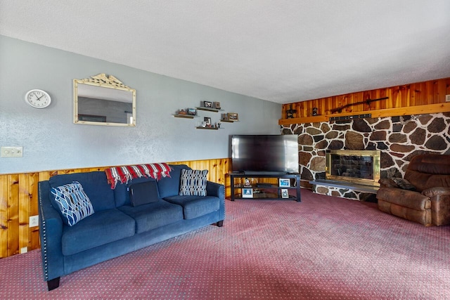 carpeted living room featuring a stone fireplace, wooden walls, and a textured ceiling