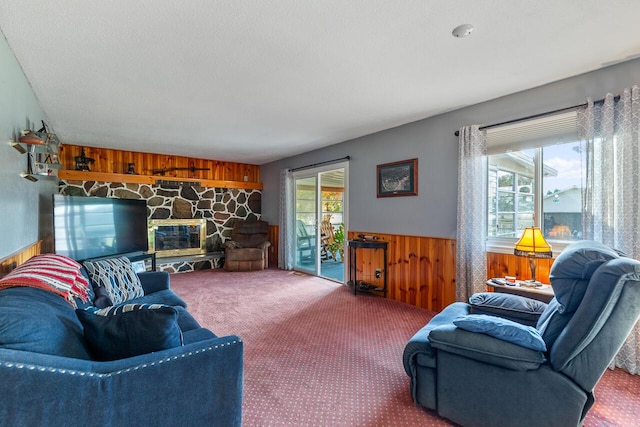 carpeted living room with a fireplace and wood walls