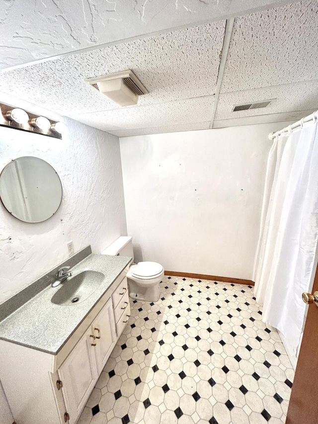 bathroom featuring toilet, vanity, and a paneled ceiling