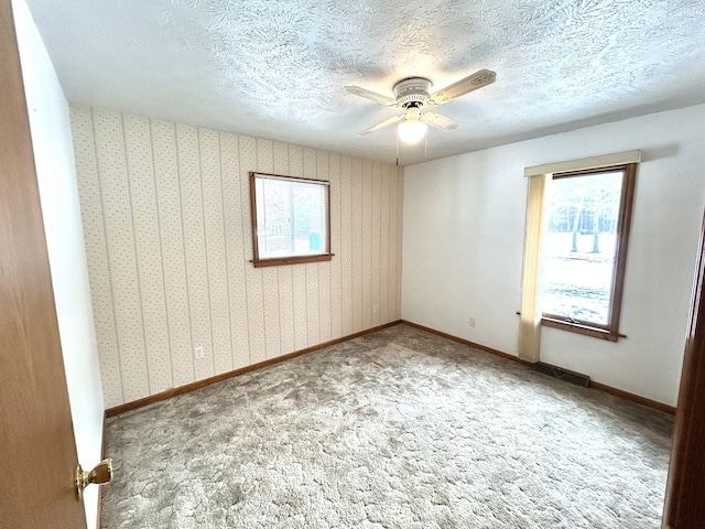 carpeted empty room featuring ceiling fan and a textured ceiling