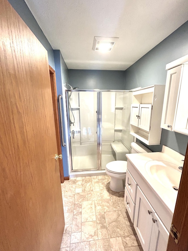 bathroom with a textured ceiling, toilet, a shower with door, and vanity