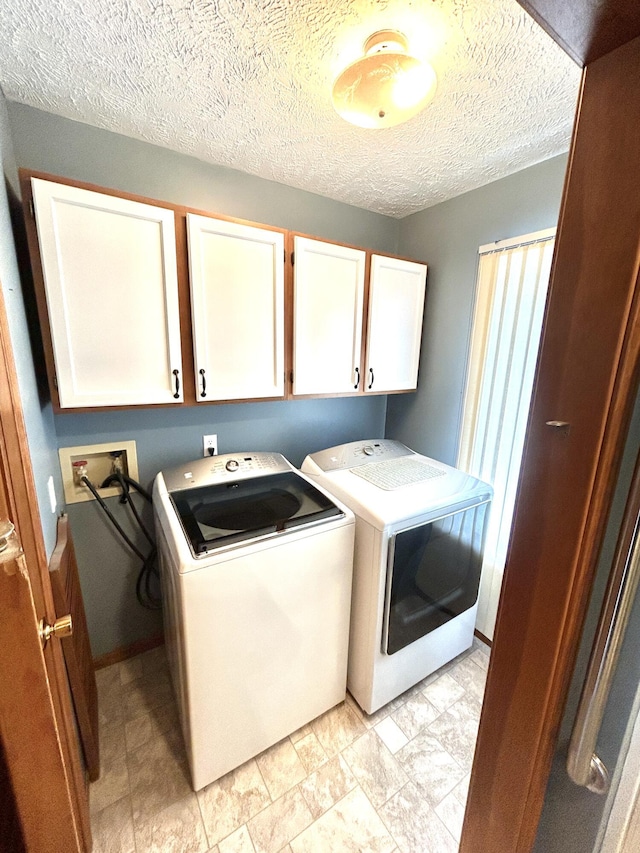 laundry room featuring cabinets, a textured ceiling, and washing machine and dryer