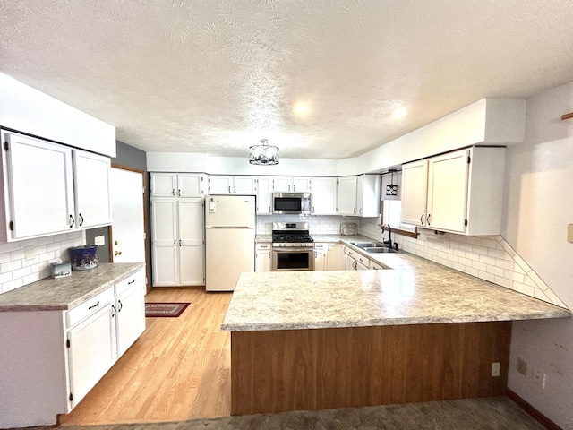 kitchen with light hardwood / wood-style floors, white cabinets, appliances with stainless steel finishes, and kitchen peninsula