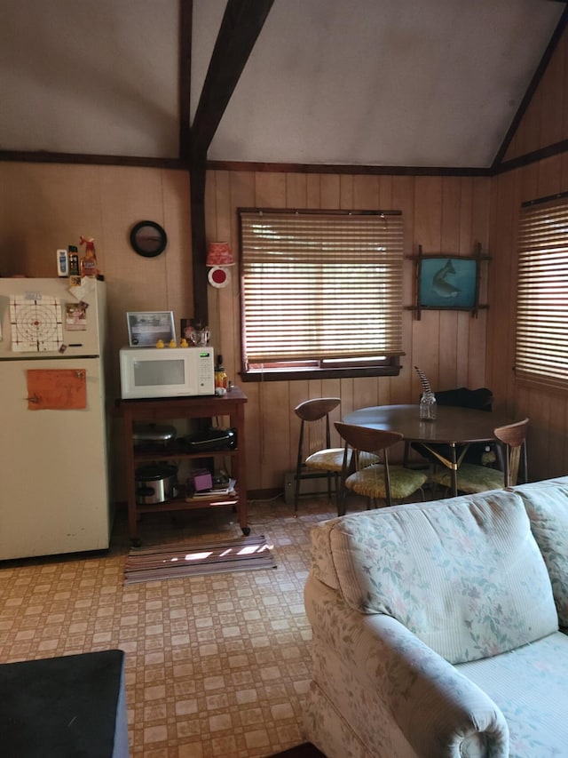 living room featuring wood walls, crown molding, and lofted ceiling with beams