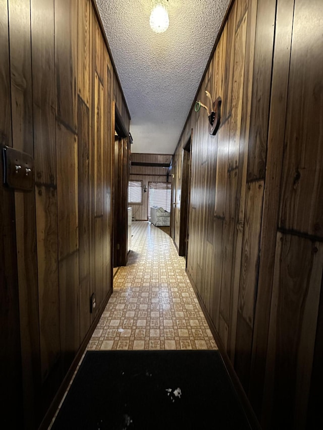 hall with wooden walls and a textured ceiling