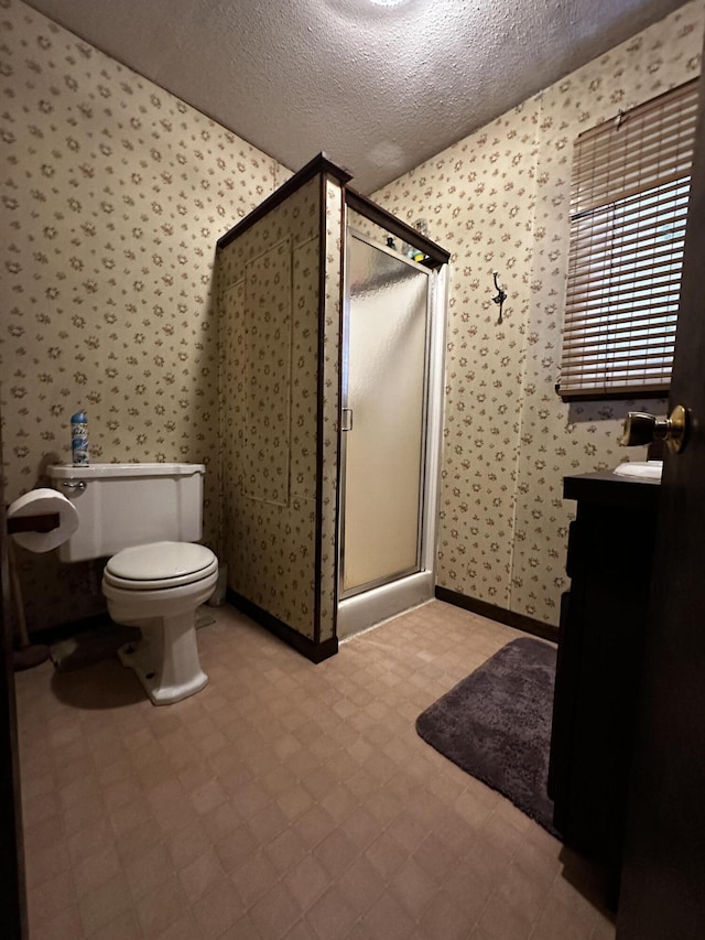 bathroom featuring vanity, toilet, an enclosed shower, and a textured ceiling