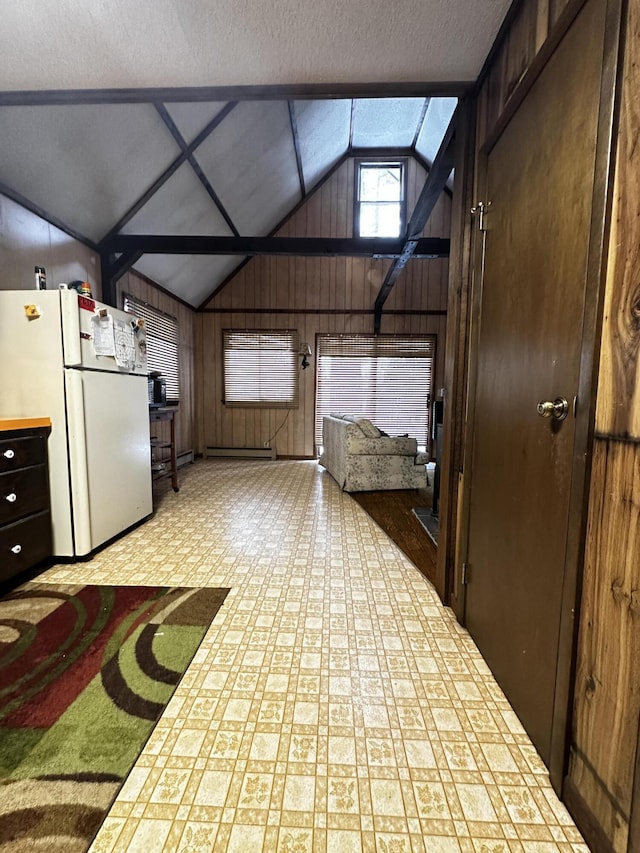 interior space featuring baseboard heating, wood walls, and vaulted ceiling