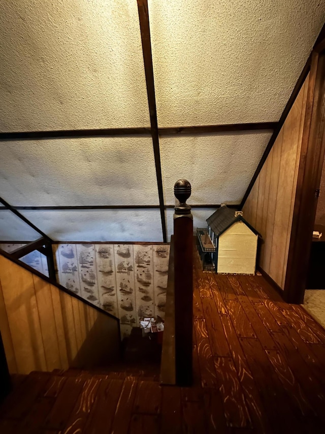 unfurnished bedroom with dark hardwood / wood-style floors, wood walls, and lofted ceiling