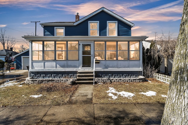 view of front facade with a chimney, fence, and a sunroom